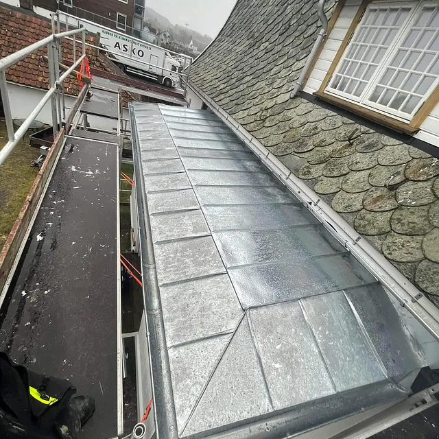 Hus med skifertak og overbygg av blikk.